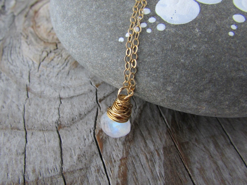 May include: A gold chain necklace with a white moonstone pendant wrapped in gold wire.