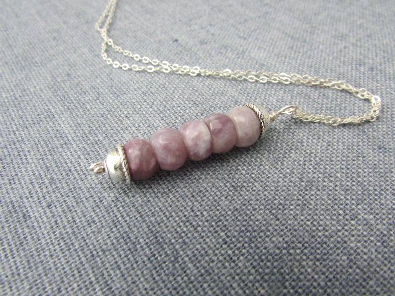 May include: A silver chain necklace with a pendant made of five round, light purple and white gemstone beads. The beads are strung on a silver wire and have a silver clasp.