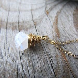 May include: A gold chain necklace with a white moonstone pendant wrapped in gold wire.