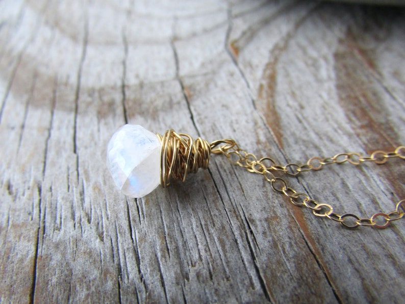 May include: A gold chain necklace with a white moonstone pendant wrapped in gold wire.