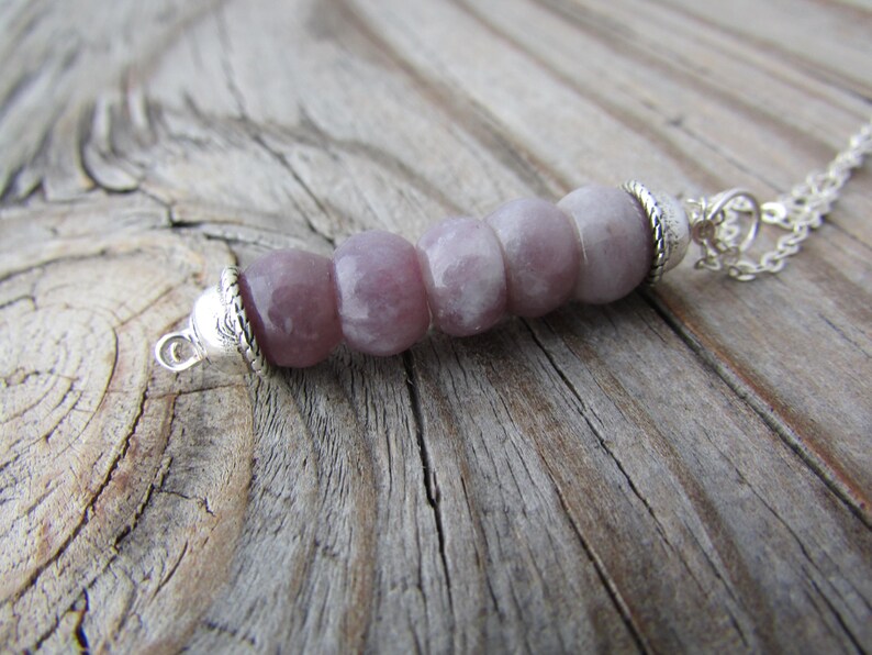 May include: A silver chain necklace with a pendant made of five light purple and white gemstone beads.