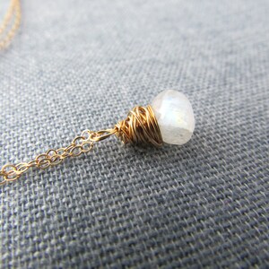 May include: A gold chain necklace with a white moonstone pendant wrapped in gold wire.
