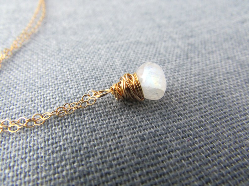 May include: A gold chain necklace with a white moonstone pendant wrapped in gold wire.