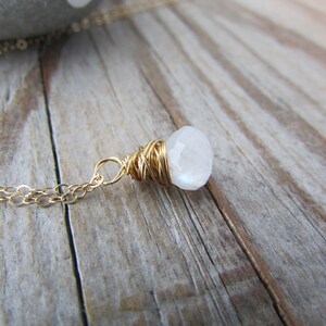 May include: A gold chain necklace with a white moonstone pendant wrapped in gold wire.