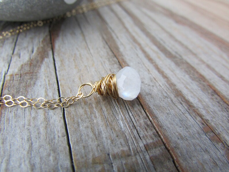 May include: A gold chain necklace with a white moonstone pendant wrapped in gold wire.
