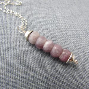 May include: A silver chain necklace with a pendant made of five round, light purple gemstone beads with silver accents.