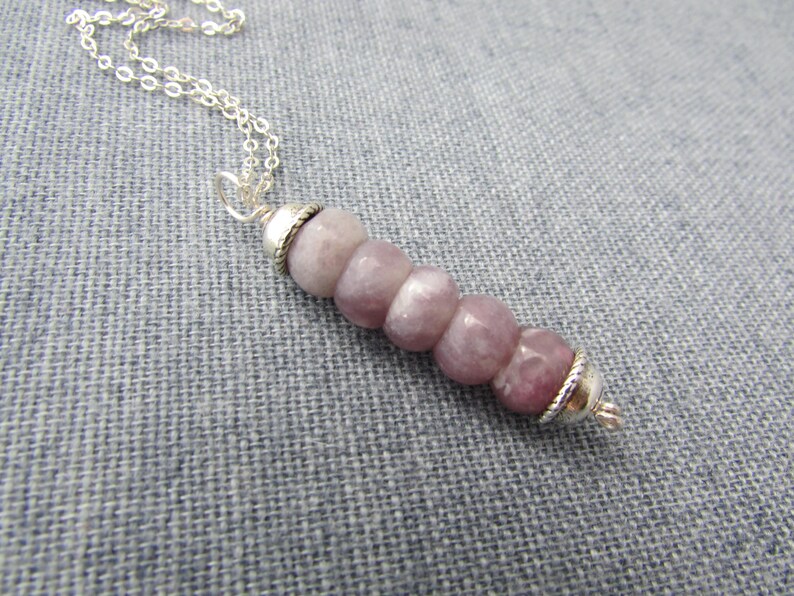 May include: A silver chain necklace with a pendant made of five round, light purple gemstone beads with silver accents.