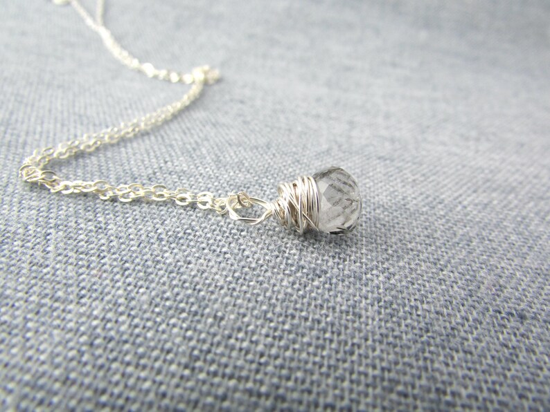 May include: A silver chain necklace with a clear quartz crystal pendant wrapped in silver wire.