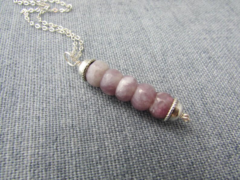 May include: A silver chain necklace with a pendant made of six round, light purple and white stones with silver accents.