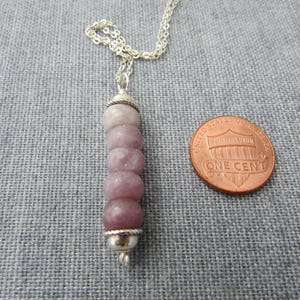 May include: A silver chain necklace with a pendant made of five stacked, light purple, round, gemstone beads with silver accents.