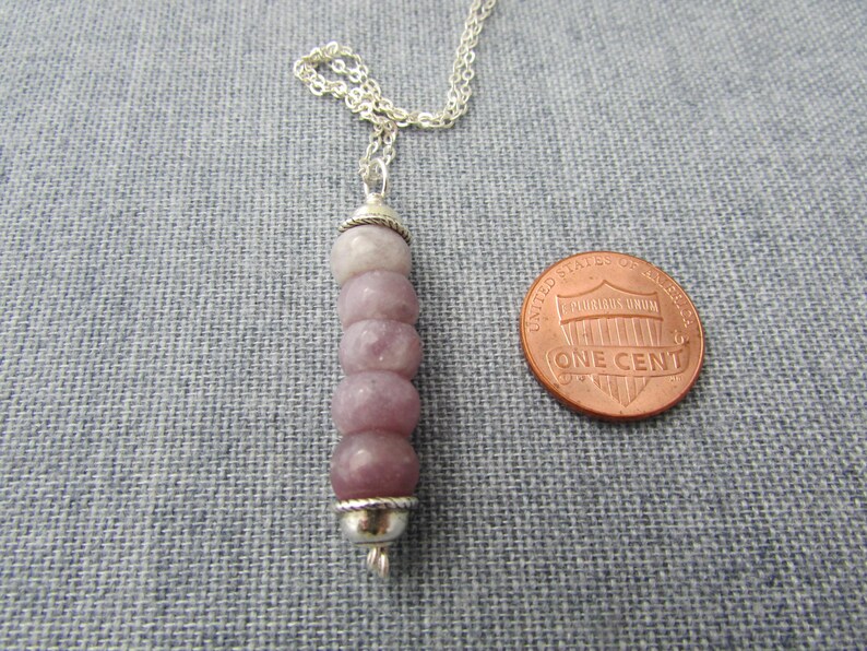 May include: A silver chain necklace with a pendant made of five stacked, light purple, round, gemstone beads with silver accents.