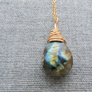 Può includere: Una collana con catena d'oro con un ciondolo a forma di lacrima in labradorite avvolto in filo d'oro.