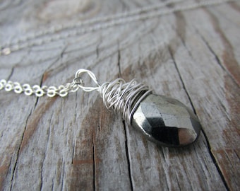 May include: A silver chain necklace with a silver wire-wrapped pyrite pendant. The pendant is a dark gray, faceted stone.