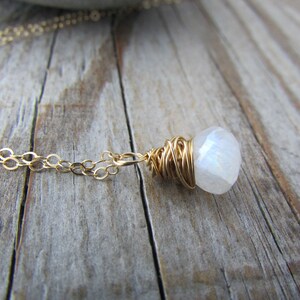 May include: A gold chain necklace with a white moonstone pendant wrapped in gold wire.