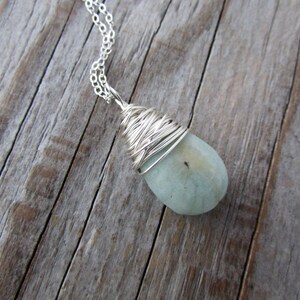 Pu&ograve; includere: Una collana con catena d'argento con una pietra a forma di lacrima di colore blu chiaro avvolta in filo d'argento.