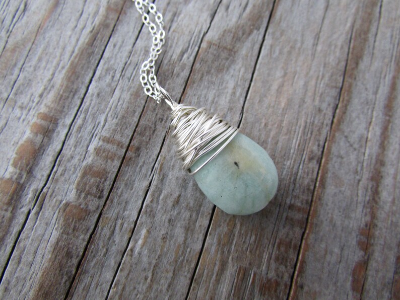 Pu&ograve; includere: Una collana con catena d'argento con una pietra a forma di lacrima di colore blu chiaro avvolta in filo d'argento.
