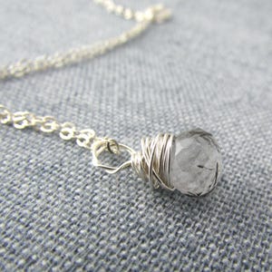 May include: A silver chain necklace with a clear quartz crystal wrapped in silver wire.