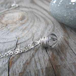 May include: A silver chain necklace with a clear quartz crystal pendant wrapped in silver wire.