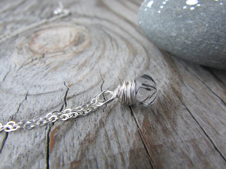 May include: A silver chain necklace with a clear quartz crystal pendant wrapped in silver wire.