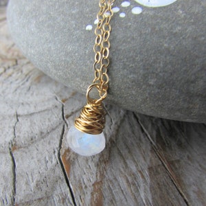 May include: A gold chain necklace with a white moonstone pendant wrapped in gold wire.