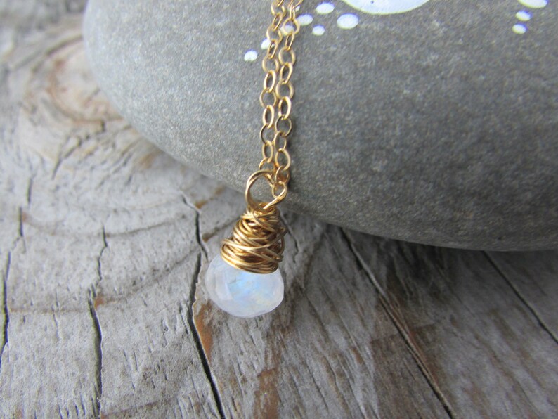 May include: A gold chain necklace with a white moonstone pendant wrapped in gold wire.