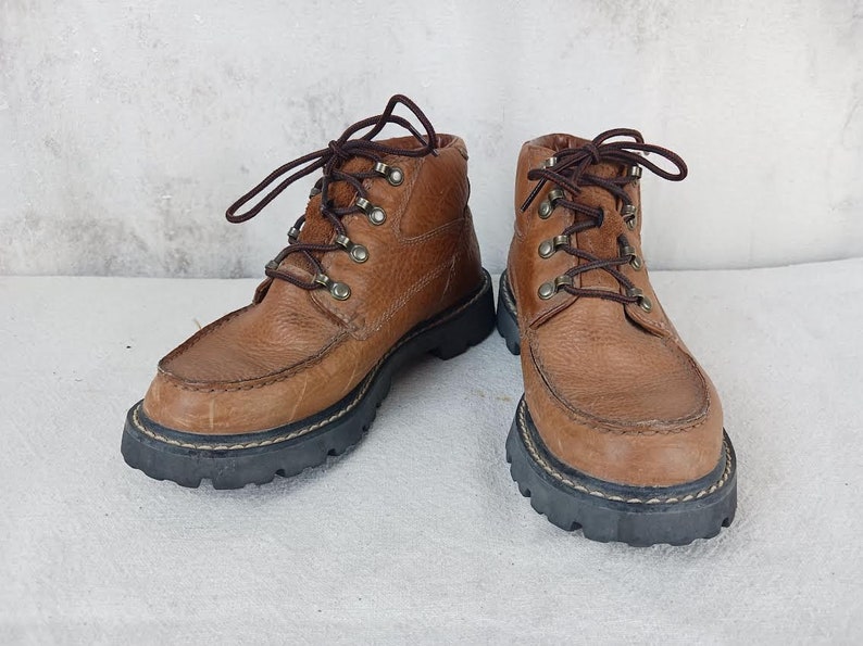 May include: A pair of brown leather hiking boots with laces and a rugged sole.