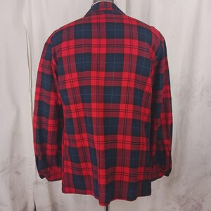 May include: A red and navy plaid shirt. The shirt has a classic plaid pattern with thick red lines and navy blue intersecting lines. The shirt has long sleeves and a button-down front.