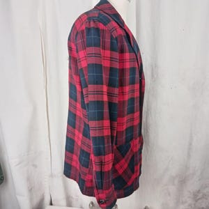 May include: A red, black, and navy plaid blazer. The blazer has a classic design with a notched lapel, long sleeves, and two front pockets. The plaid pattern is a bold and eye-catching design.