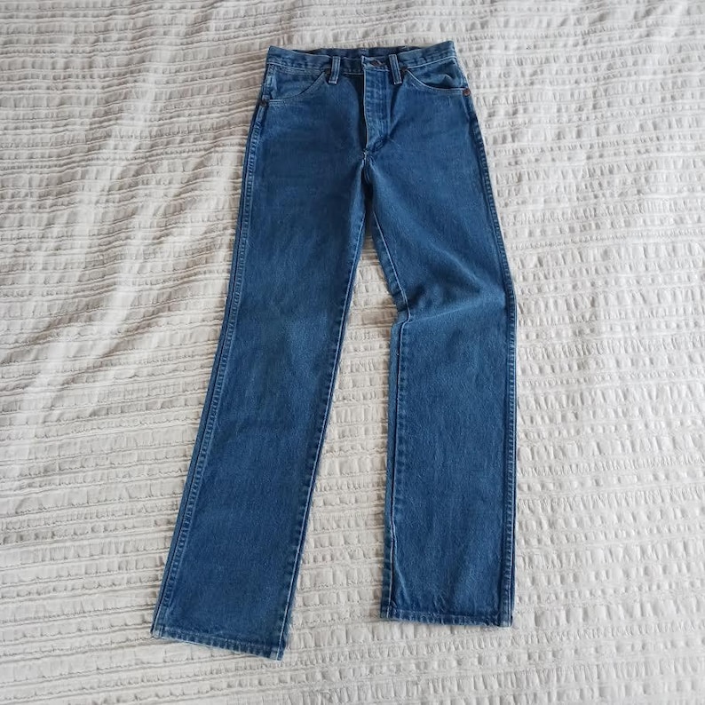 May include: A pair of blue denim jeans with a button fly and five pockets.