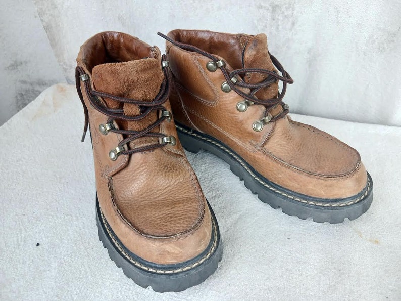 May include: A pair of brown leather ankle boots with laces and metal eyelets. The boots have a thick rubber sole.