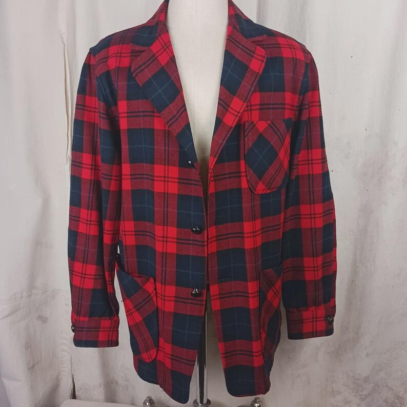 May include: A red and navy plaid blazer with a classic design. The blazer features a notched lapel, three black buttons, and two front pockets. The jacket is displayed on a mannequin.