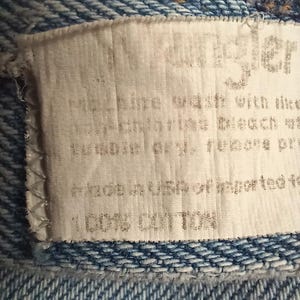 Puede incluir: Una etiqueta blanca con texto negro que dice "angler" y "100% algod&oacute;n" e instrucciones de cuidado. La etiqueta est&aacute; unida a una tela vaquera azul.