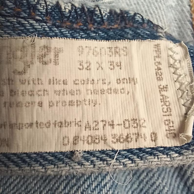 Puede incluir: Una etiqueta blanca con texto negro que dice "#760383 32 x 34" y "of imported fabric A274-0512 04034 36471 0".