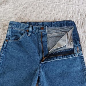 May include: A pair of blue denim jeans with a zipper fly and a button closure. The jeans have a classic five-pocket style and a straight leg.