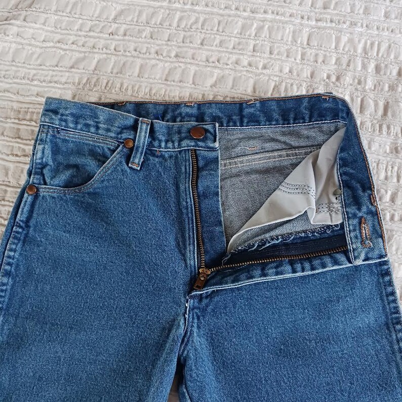 May include: A pair of blue denim jeans with a zipper fly and a button closure. The jeans have a classic five-pocket style and a straight leg.