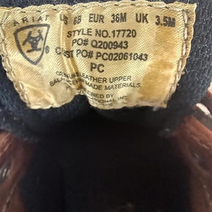 May include: Brown leather Ariat boot with a size tag that reads "68 EUR 36M UK 3.5M", "STYLE NO. 17720", "PO# Q200943", "CUST PO# PC02061043", "PC", "GENUINE LEATHER UPPER", "BALANCES MADE MATERIALS", "ERED BY", "TIONAL INC".