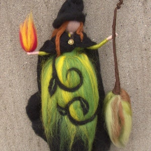 May include: A felt witch doll with a black hat, green and yellow dress, and a brown twig broom. The doll is holding a flame in one hand.