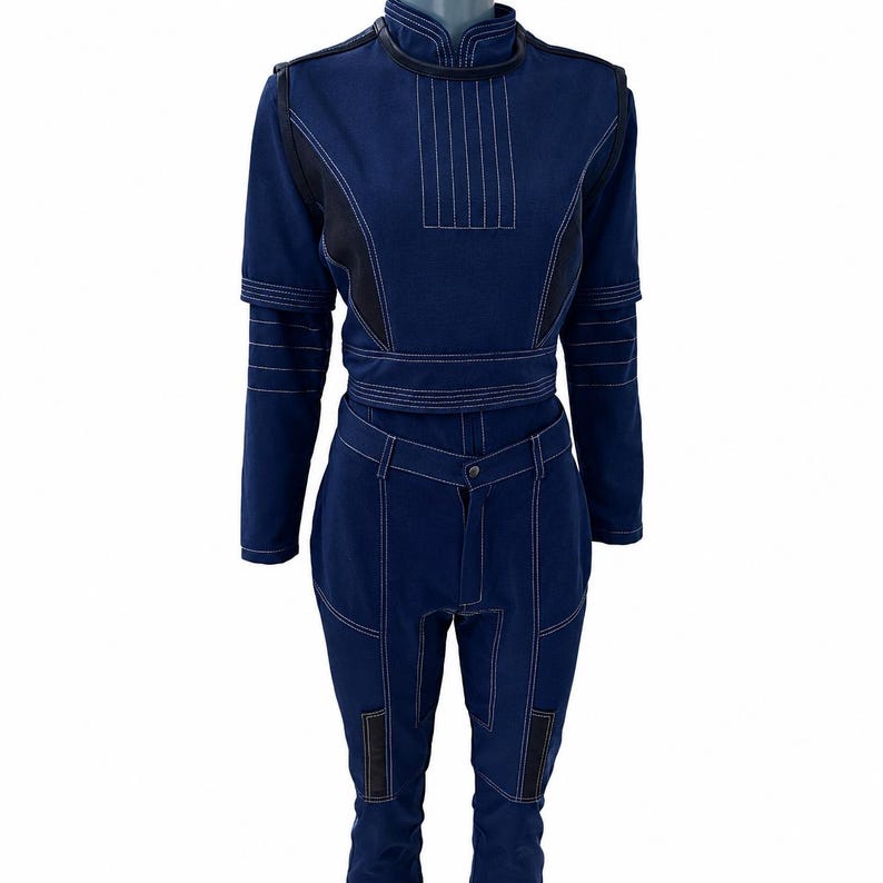 May include: A two-piece denim outfit in a dark blue hue, featuring white stitching and black accents. The top has a high collar and long sleeves, while the pants have a button closure and pockets. The outfit is displayed on a mannequin.