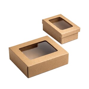 Pu&ograve; includere: Due scatole rettangolari in cartone marrone con finestre in plastica trasparente sui coperchi. Le scatole sono realizzate in carta marrone chiaro e presentano un design con coperchio rimovibile, con una scatola pi&ugrave; grande in primo piano.