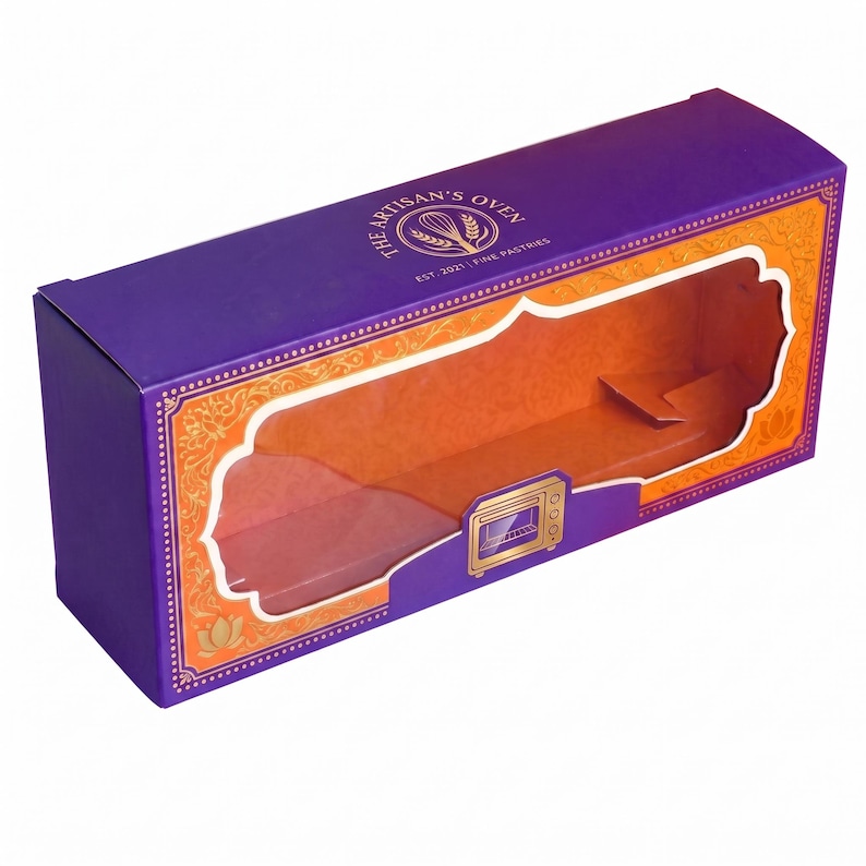 May include: A rectangular purple cardboard box with an orange interior and a large, decorative clear window on the front. The top features the text "THE ARTISAN'S OVEN" with a whisk logo, and a small gold oven icon is printed below the window.