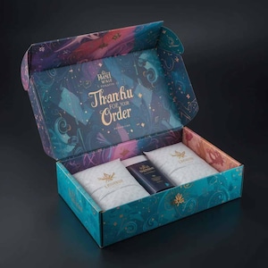 Peut inclure: Une boîte décorative ouverte avec un design turquoise, violet et or. L'intérieur de la boîte contient deux paquets blancs et un produit bleu foncé. Le couvercle de la boîte indique "Thank you for your order."
