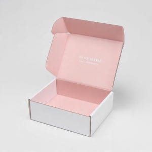 Pu&ograve; includere: Una scatola di spedizione rettangolare in cartone aperta con esterno bianco e interno rosa tenue. Il coperchio interno presenta il testo stampato in bianco Grace Eleyae e la frase Live confidently in un carattere sans-serif.