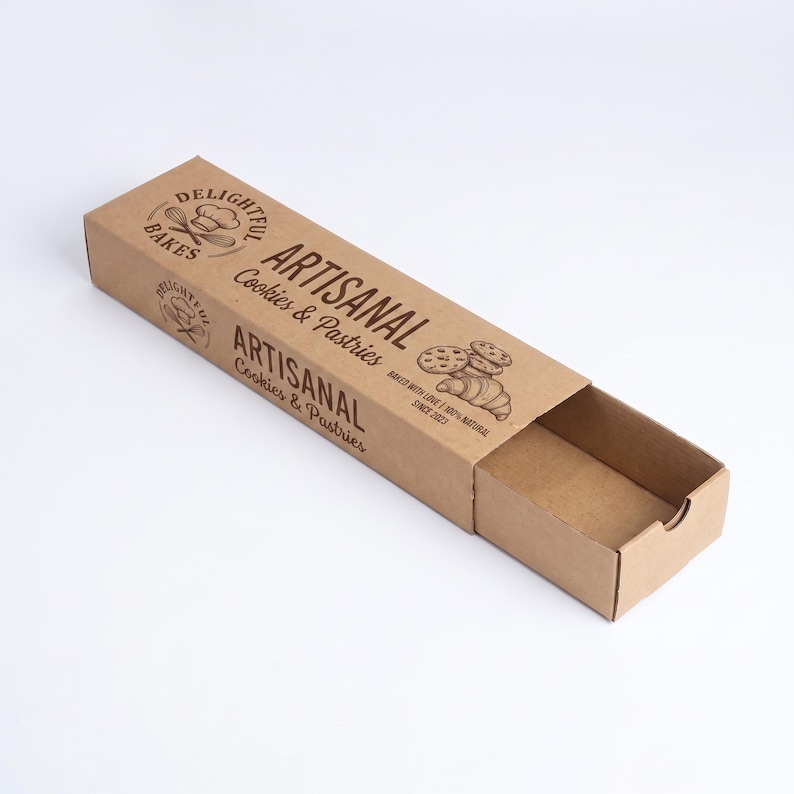 May include: A rectangular brown cardboard sliding box for cookies and pastries. The top and side feature dark brown text reading "DELIGHTFUL BAKES," "ARTISANAL Cookies & Pastries," "BAKED WITH LOVE," "100% NATURAL," and "SINCE 2023" with illustrations of a whisk, chef hat, cookies, and a croissant.