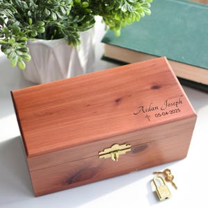 May include: A wooden keepsake box with a brass latch and lock. The box is engraved with the name "Aidan Joseph" and the date "05-04-2025".