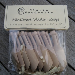 May include: A package of 12 natural wood miniature scoops, measuring 1.25 inches by 3 inches. The scoops are packaged in a clear plastic bag with a brown paper label that reads "Clarke Woodworks Miniature Wooden Scoops".