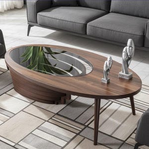 Op de afbeelding: Ovale salontafel van donkerbruin hout met een glazen inzetstuk. Twee zilveren sculpturen staan op de tafel. De tafel wordt omringd door grijze meubels en een patroonkleed.