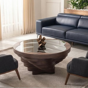 May include: A contemporary living room arrangement with a navy blue leather sofa, two grey armchairs, and a distinctive spiral coffee table with a glass surface. The room is bright with neutral curtains.