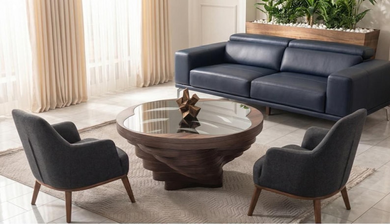 May include: A contemporary living room arrangement with a navy blue leather sofa, two grey armchairs, and a distinctive spiral coffee table with a glass surface. The room is bright with neutral curtains.