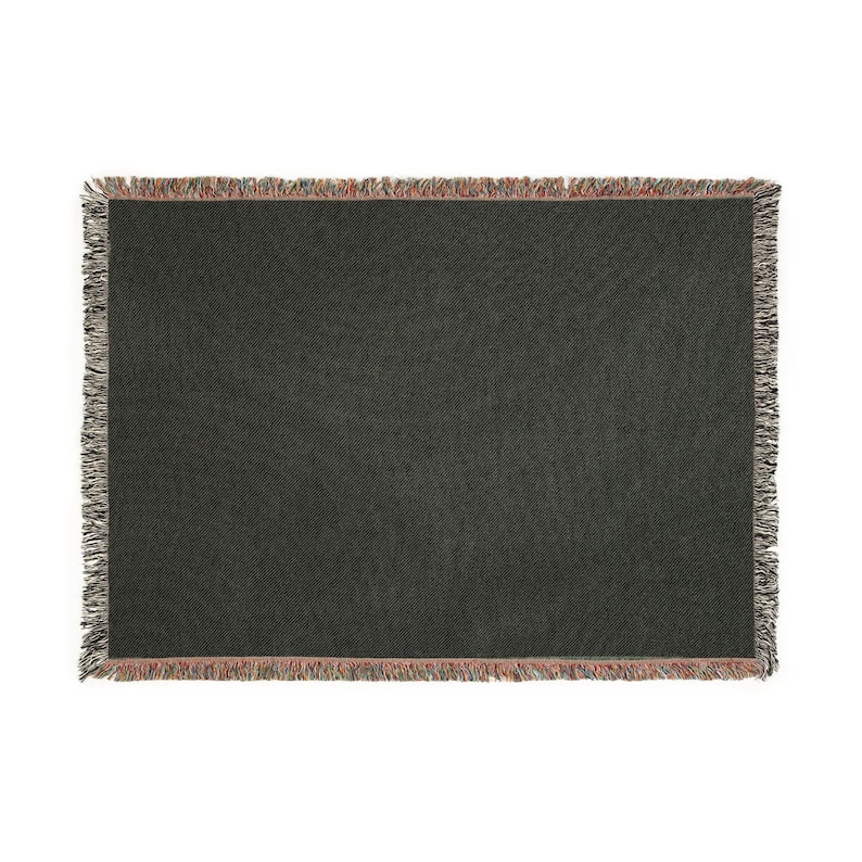 May include: A dark gray woven throw blanket with a textured pattern. The blanket has a fringed edge with a mix of colors including red, brown, and gray. The blanket is rectangular and appears to be made of a soft material.