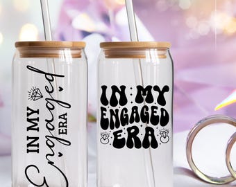May include: Two clear glass can-shaped tumblers with bamboo lids and clear straws. One tumbler has the text "IN MY Engaged ERA" in black script, and the other says "IN MY ENGAGED ERA" in a retro font. Both have diamond graphics.